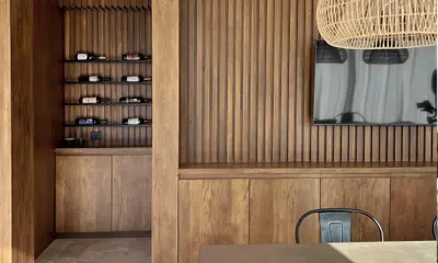 Living con revestimiento de madera, cava empotrada y una lámpara colgante de fibras naturales.